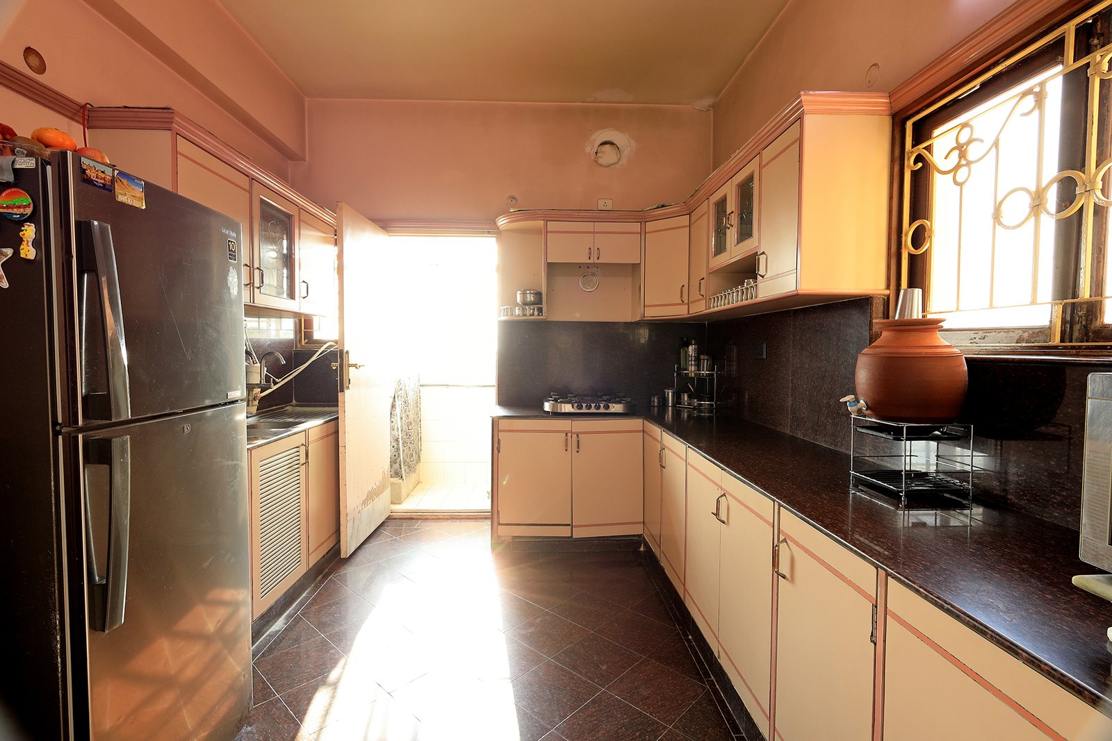 Well-lit kitchen with the attached wet-area balcony and refrigerator